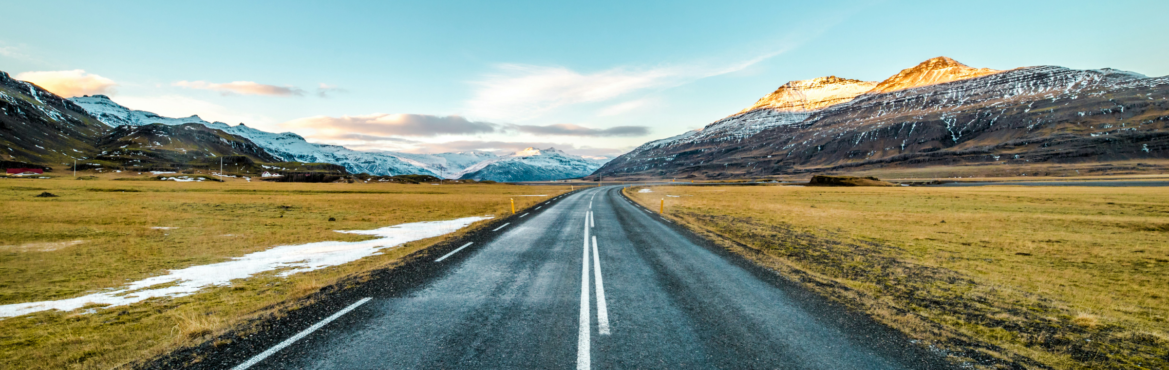An open road curving toward snow-capped mountains