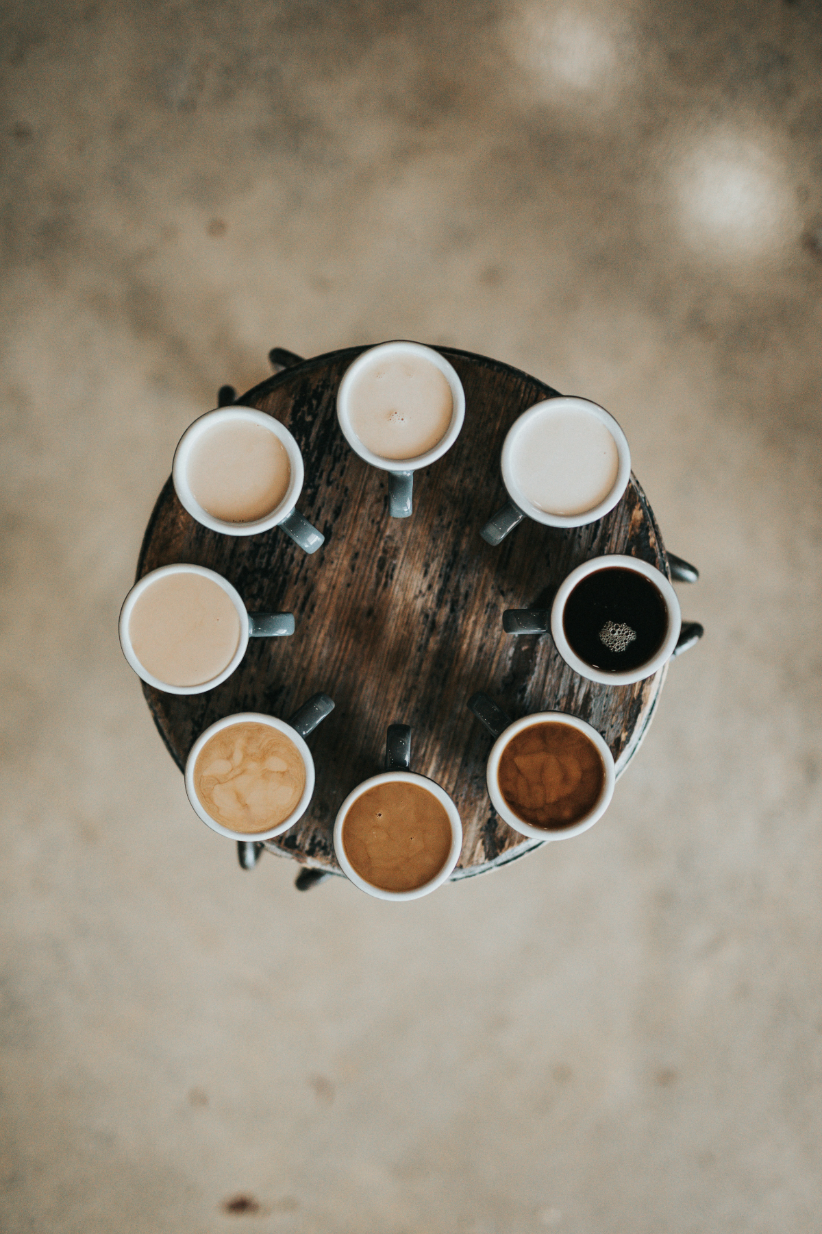 Eight coffee cups arranged in a circle on a small table, seen from above